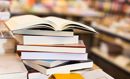 a stack of books with one book opened on top representing knowledge related to 7 essential topics for growth and learning