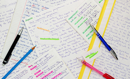 scattered notes and pens on a desk showcasing study materials for 4 college courses