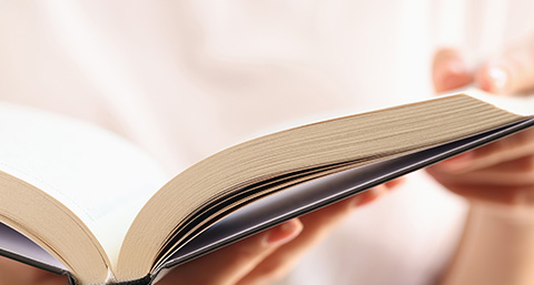 open book with visible pages being held by hands reading three chapters