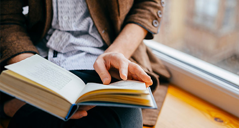 person reading a book while seated by a window enjoying a quiet moment two pages being turned