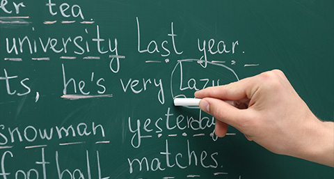 A hand writing on a chalkboard with text related to university and laziness in an educational setting about learning and knowledge